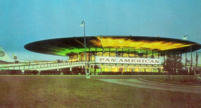 1960s A twilight shot of the Pan Am WorldPort Terminal at New York JFK airport.  Aircraft parked nose in so the extended roof could protect passengers from rain & snow.  The idea for this design came from Berlin's Tempelhof Airport that offered passengers a completely covered ramp area.